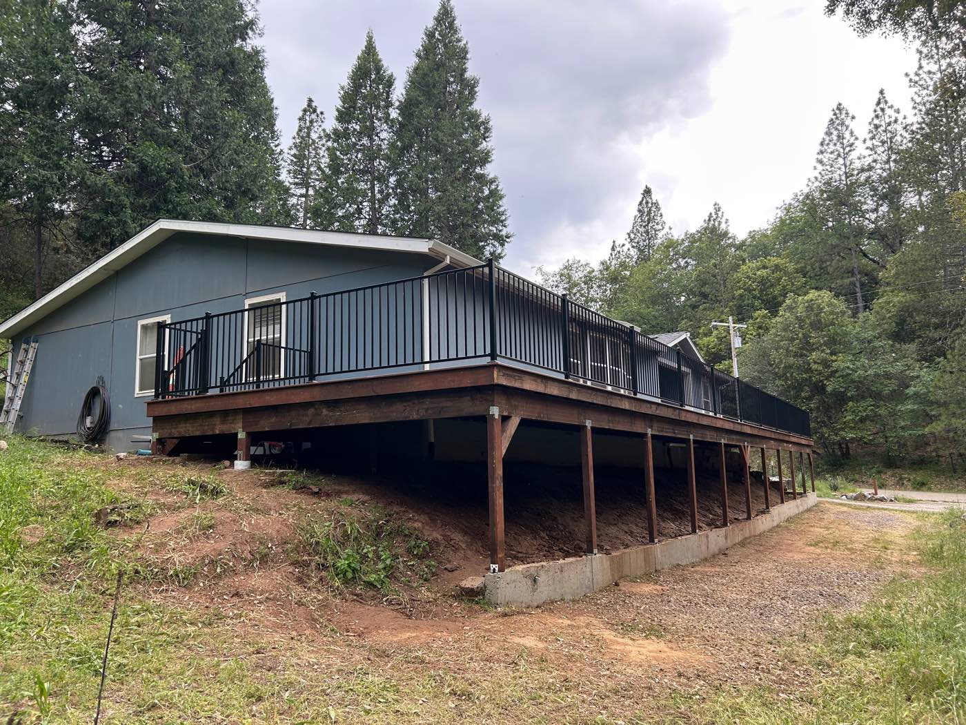 Elevated composite deck wrapping a home, with black steel railing