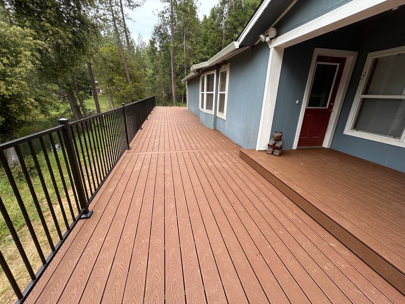 Long wrap-around composite deck walkway alongside a house
