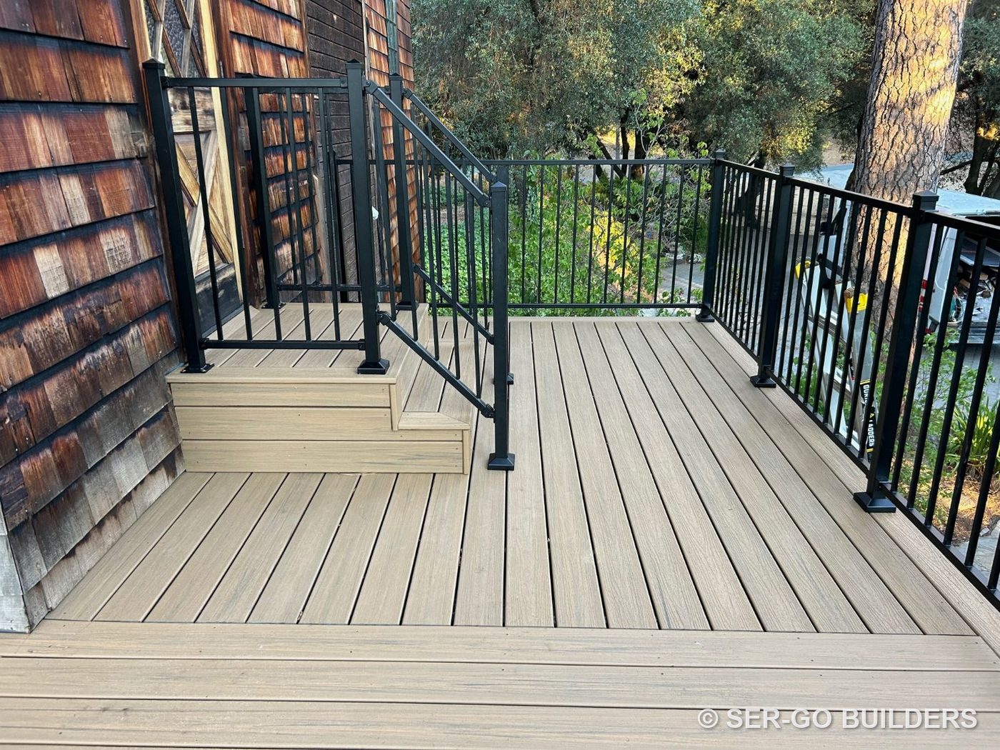 Composite deck with a built-up landing and steps at the door, framed by black steel railing