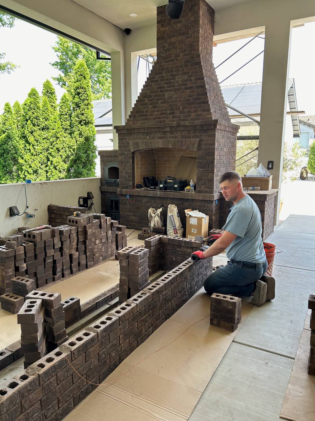 Mason laying block for an outdoor fireplace and kitchen build