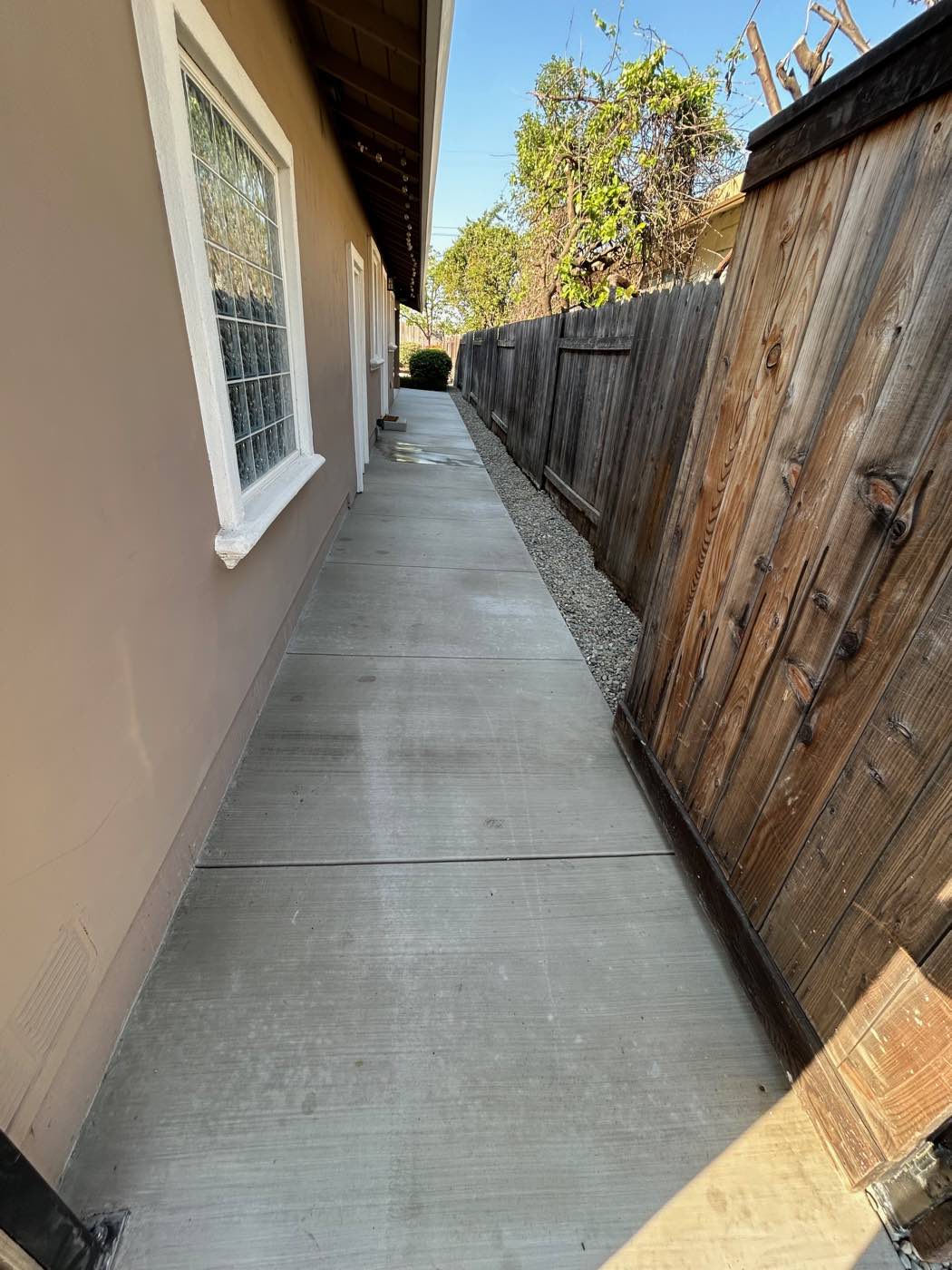 Poured concrete pathway running along the side of a home