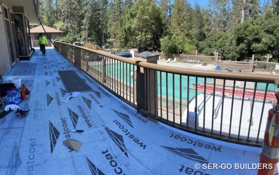 Crew installing a waterproof membrane on a long second-floor walkway