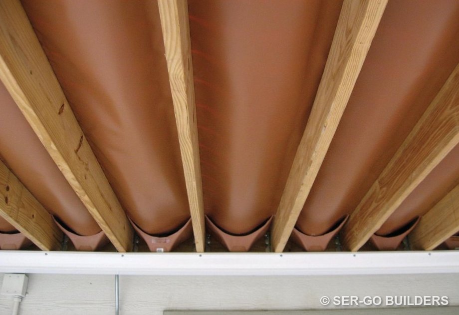 Under-deck drainage troughs seen from below, channeling water to a gutter
